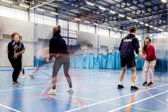 Students throw balls as they jog during a practical session