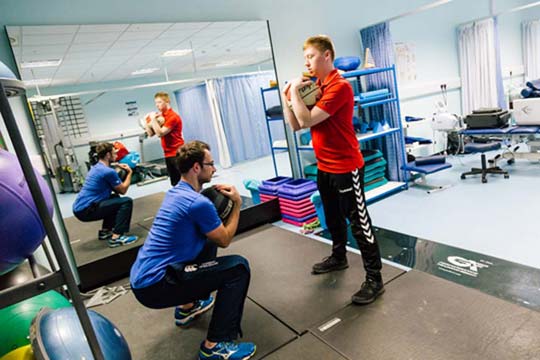 Students practicing sports rehabilitation techniques with medicine balls